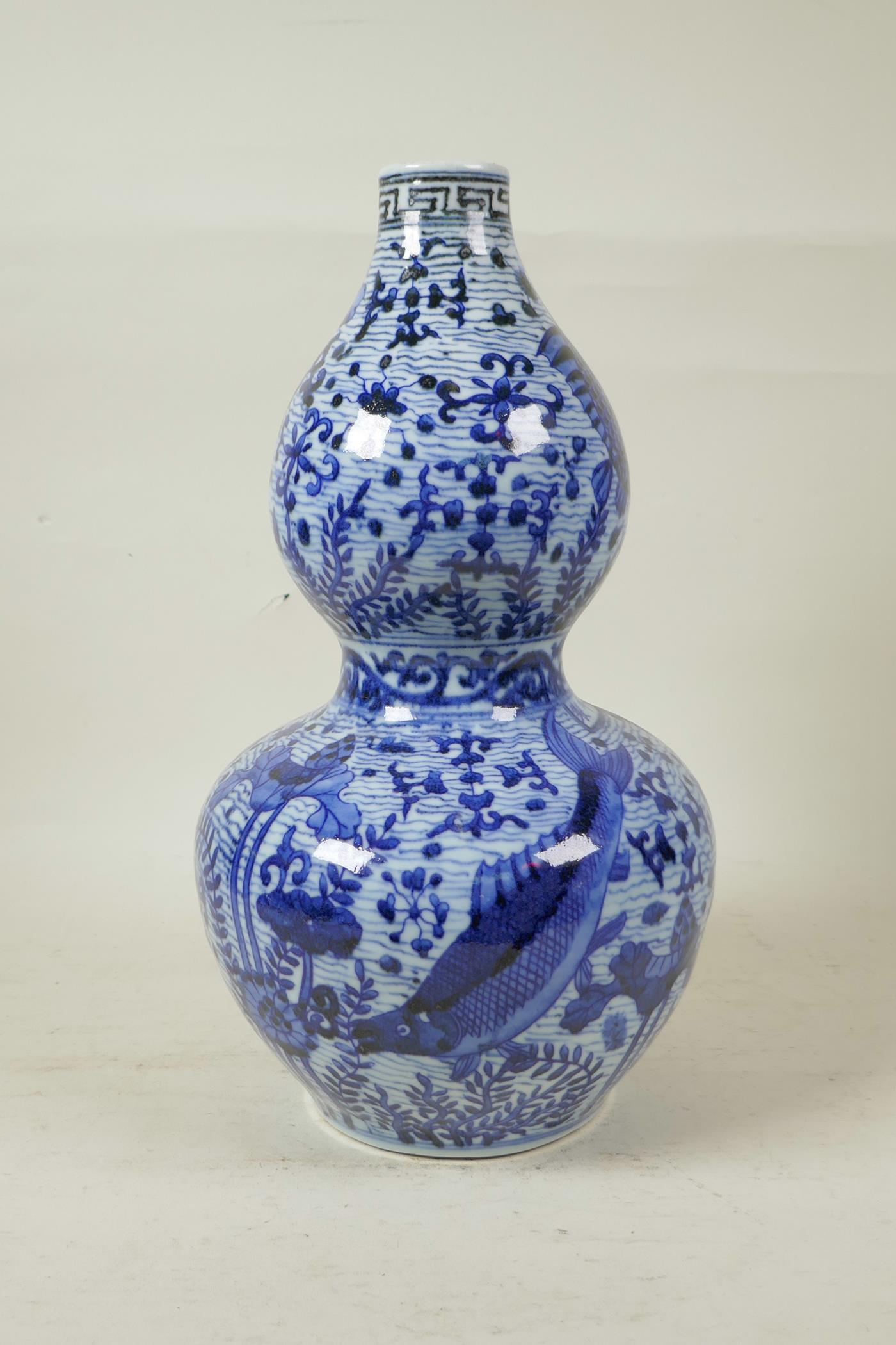 A Chinese Ming style blue and white porcelain double gourd vase decorated with carp in a lotus pond, - Image 4 of 6