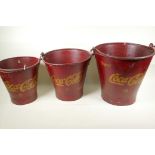 A set of three graduated metal buckets painted in red and with the Coca-Cola emblem, largest 14"