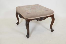 A C19th carved walnut stool of serpentine shape on cabriole supports with tapestry upholstery, 16"