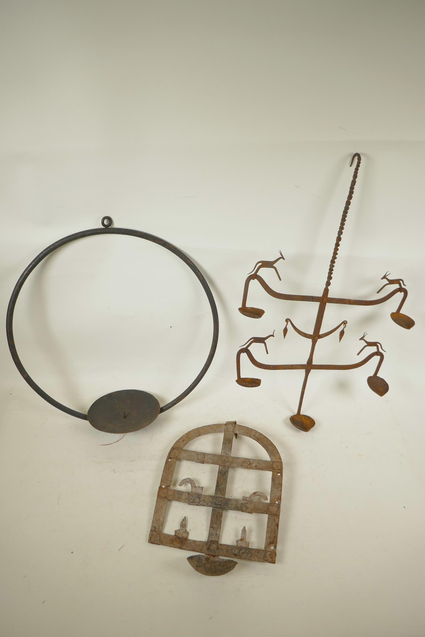 An Indian wrought iron hanging pricket candle holder, together with two riveted iron all bracket oil