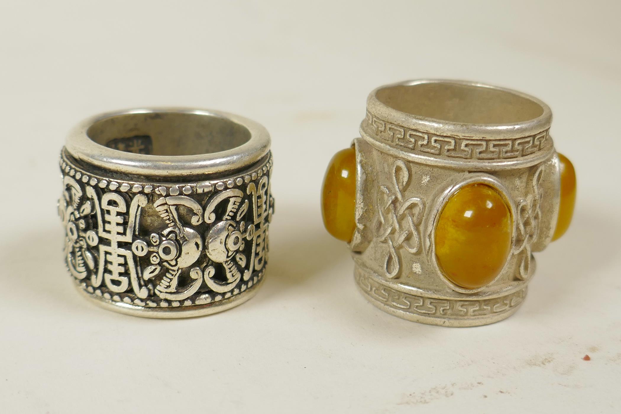 A Chinese white metal archer's thumb ring with a revolving cuff decorated with bats and symbols, and