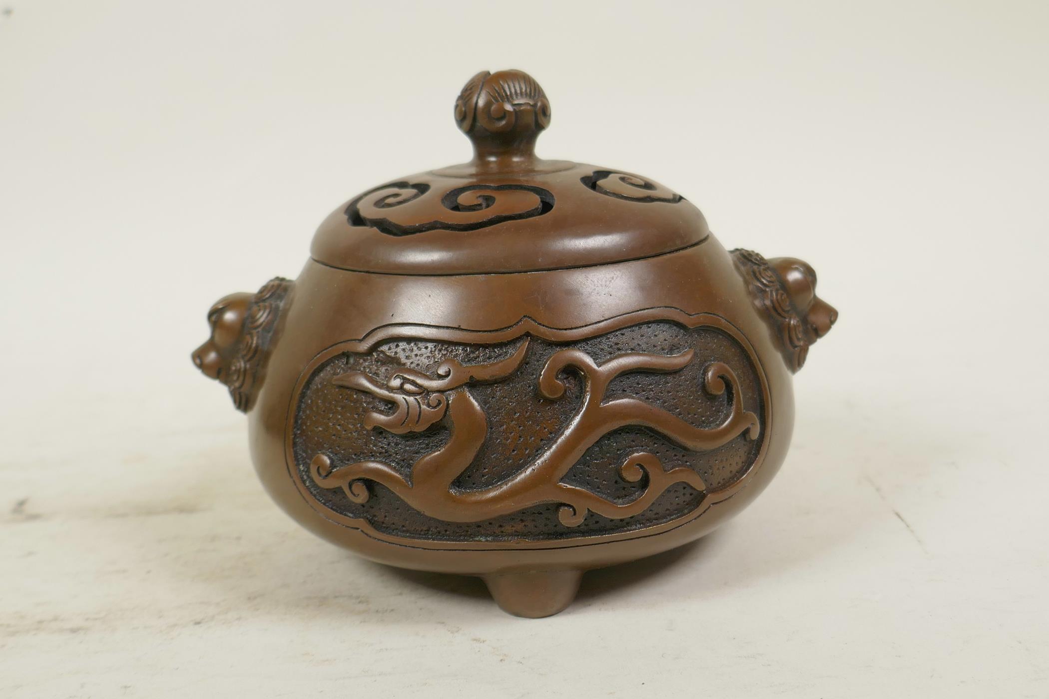 A Chinese bronze censer and cover with two lion mask handles, tripod feet and decorative dragon