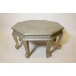 An Indian octagonal topped low table with repousse white metal decoration, raised on eight shaped