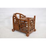 A Chinese child's chair with yoke back, latticed sides and lift out cover, raised on wood wheels,