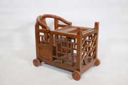 A Chinese child's chair with yoke back, latticed sides and lift out cover, raised on wood wheels,