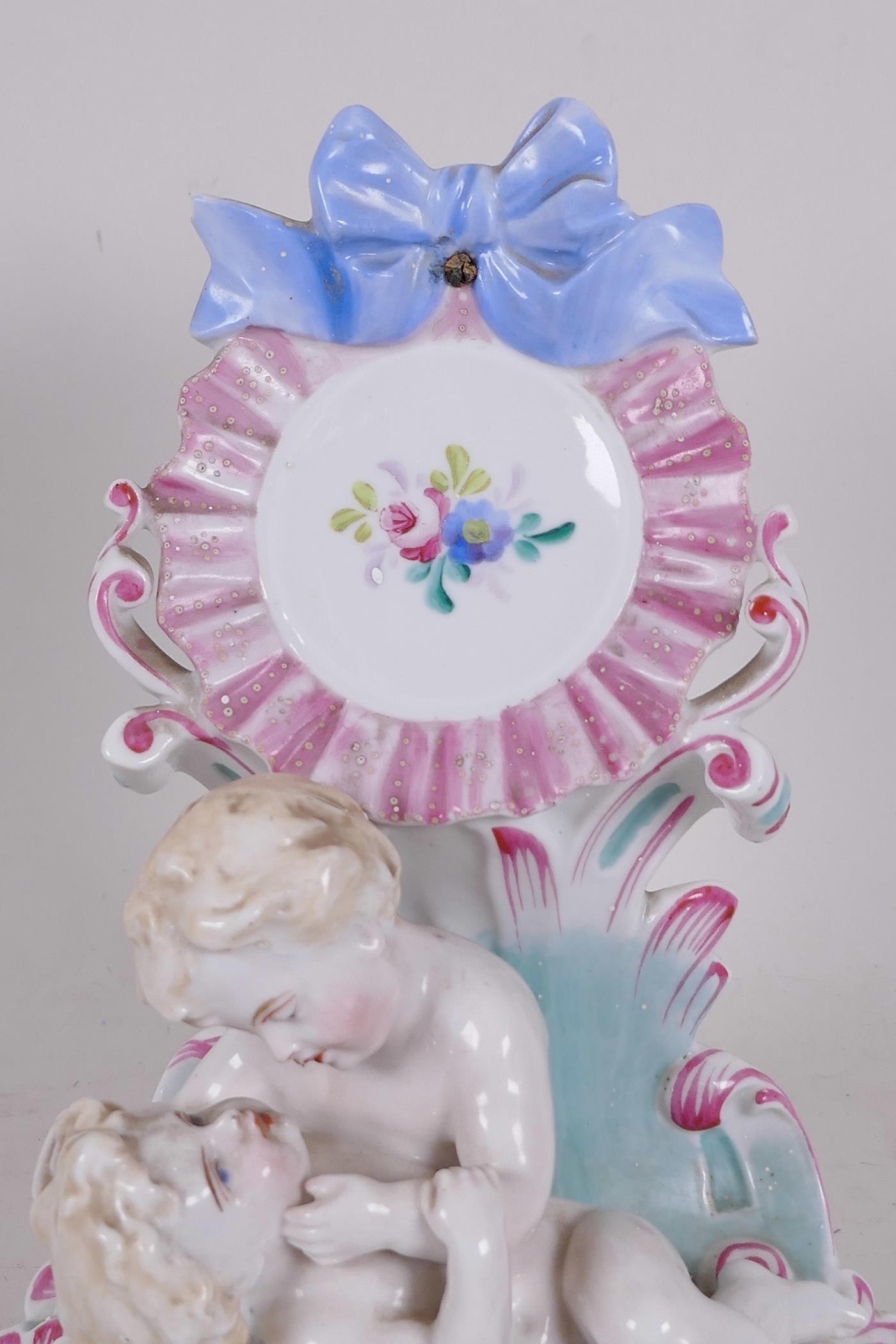 A C19th Continental porcelain watch holder formed as two children in a garden hand painted with - Image 2 of 3