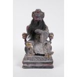 A Chinese carved, patinated and giltwood figure of an emperor seated on a throne, with a human