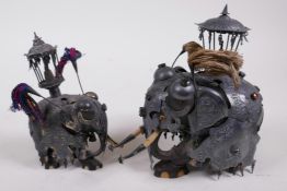 A pair of antique Indian ebony figures of elephants in metal armour and howdah with bejewelled