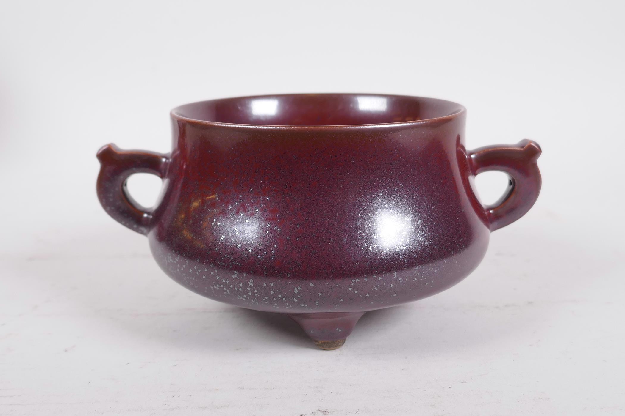 A Chinese iridescent copper glazed porcelain censer raised on tripod supports with two handles,