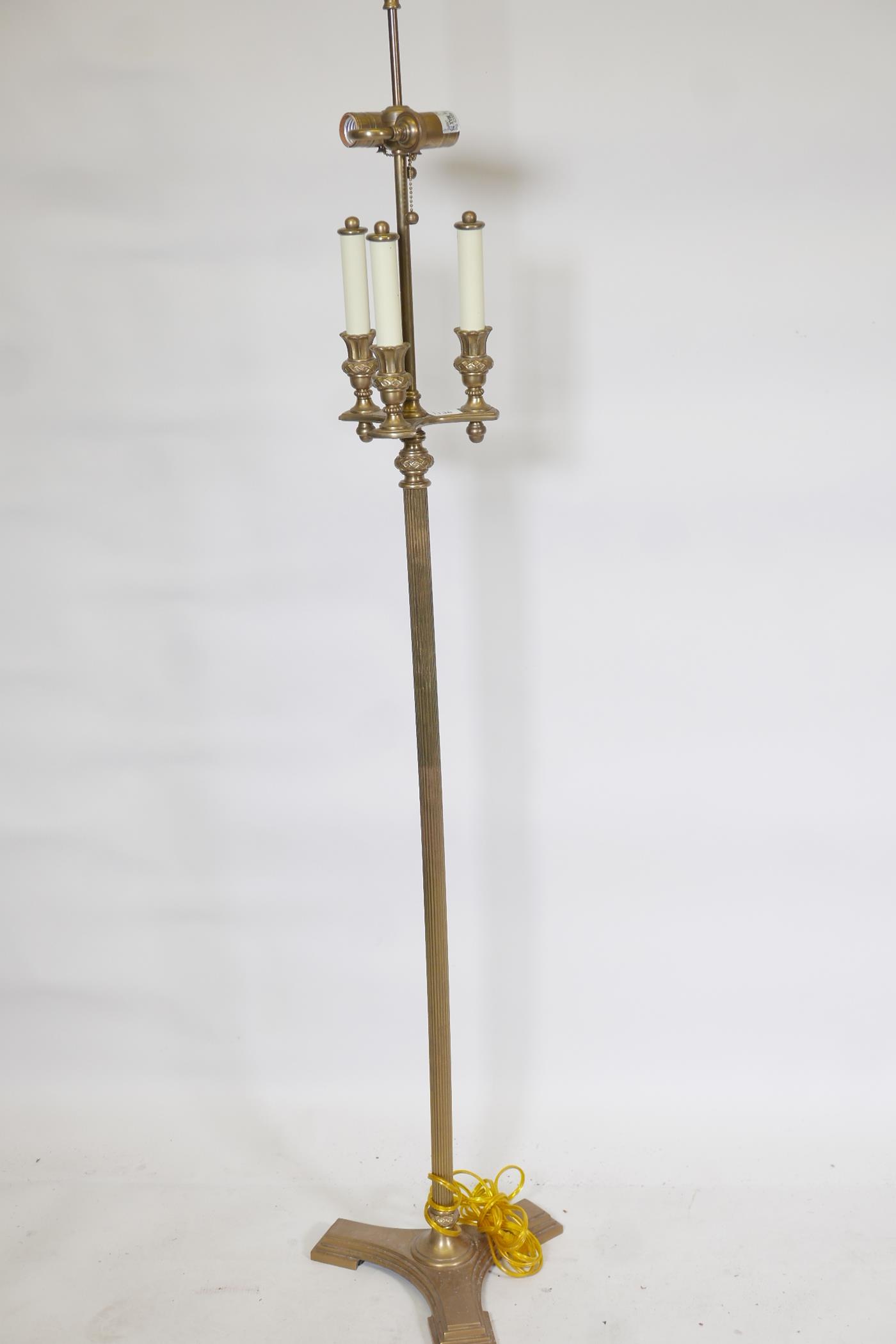 A brass three branch, two light standard lamp, with fluted column and triform base, 62" high