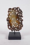 A Chinese pierced jade ornament, carved in the form of a bird headed man entwined with dragons, on a