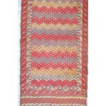 An Afghan wool runner with a repeating geometric zig zag design in red, grey and cream, woven on