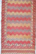 An Afghan wool runner with a repeating geometric zig zag design in red, grey and cream, woven on