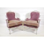 A pair of Continental Louis XV style armchairs with silver leafed decoration and distressed silk