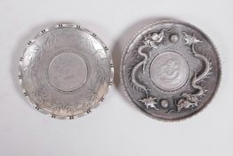 A Chinese white metal coin dish with raised dragon decoration, and another with bamboo decoration,
