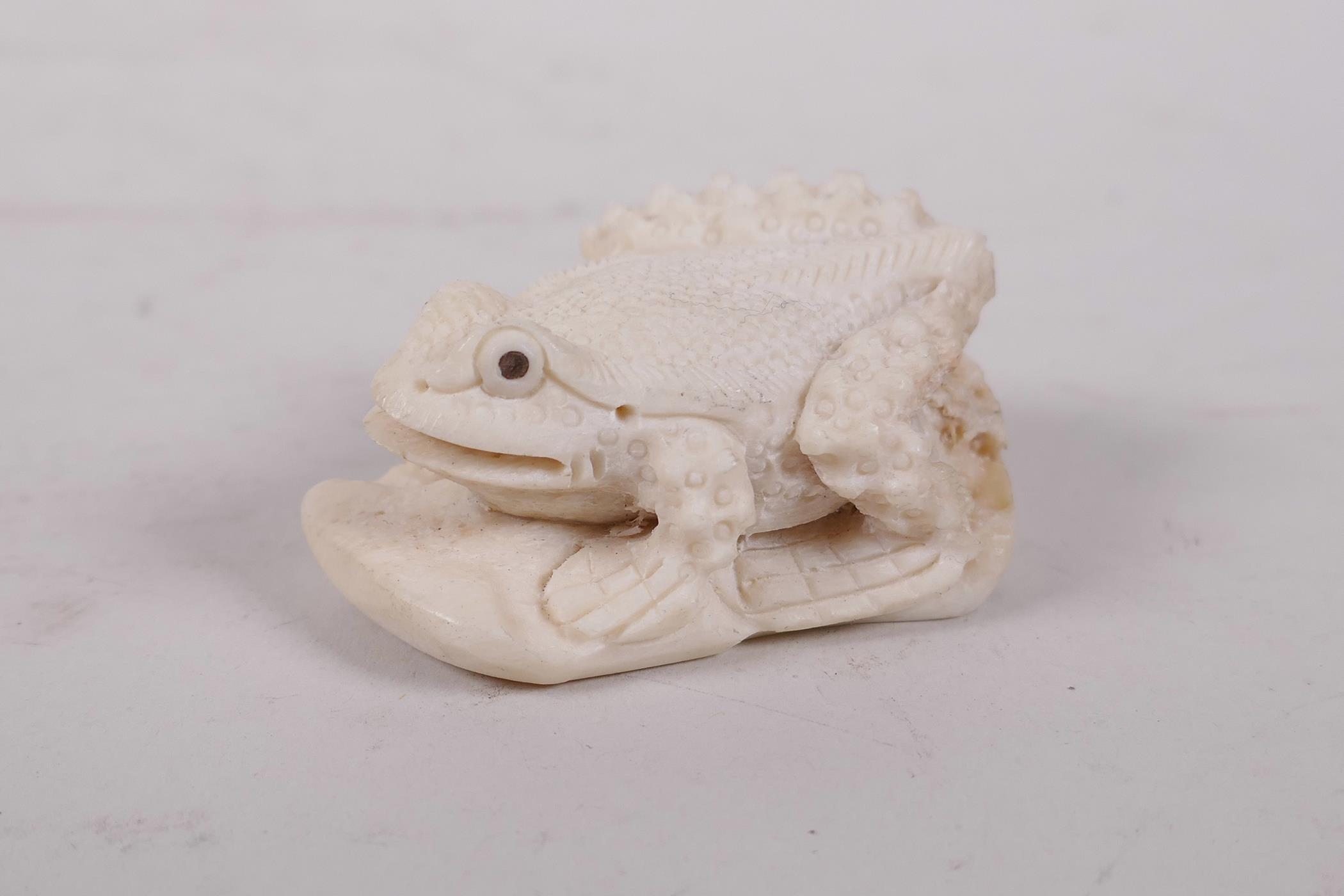 A carved bone netsuke in the form of a toad, 2" long