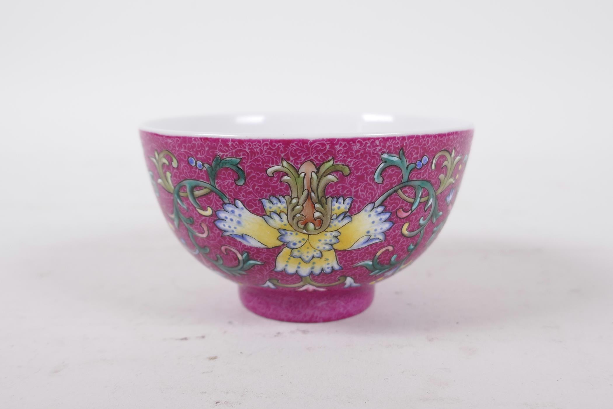 A Chinese polychrome porcelain tea bowl, with enamel lotus flower decoration on a pink ground,