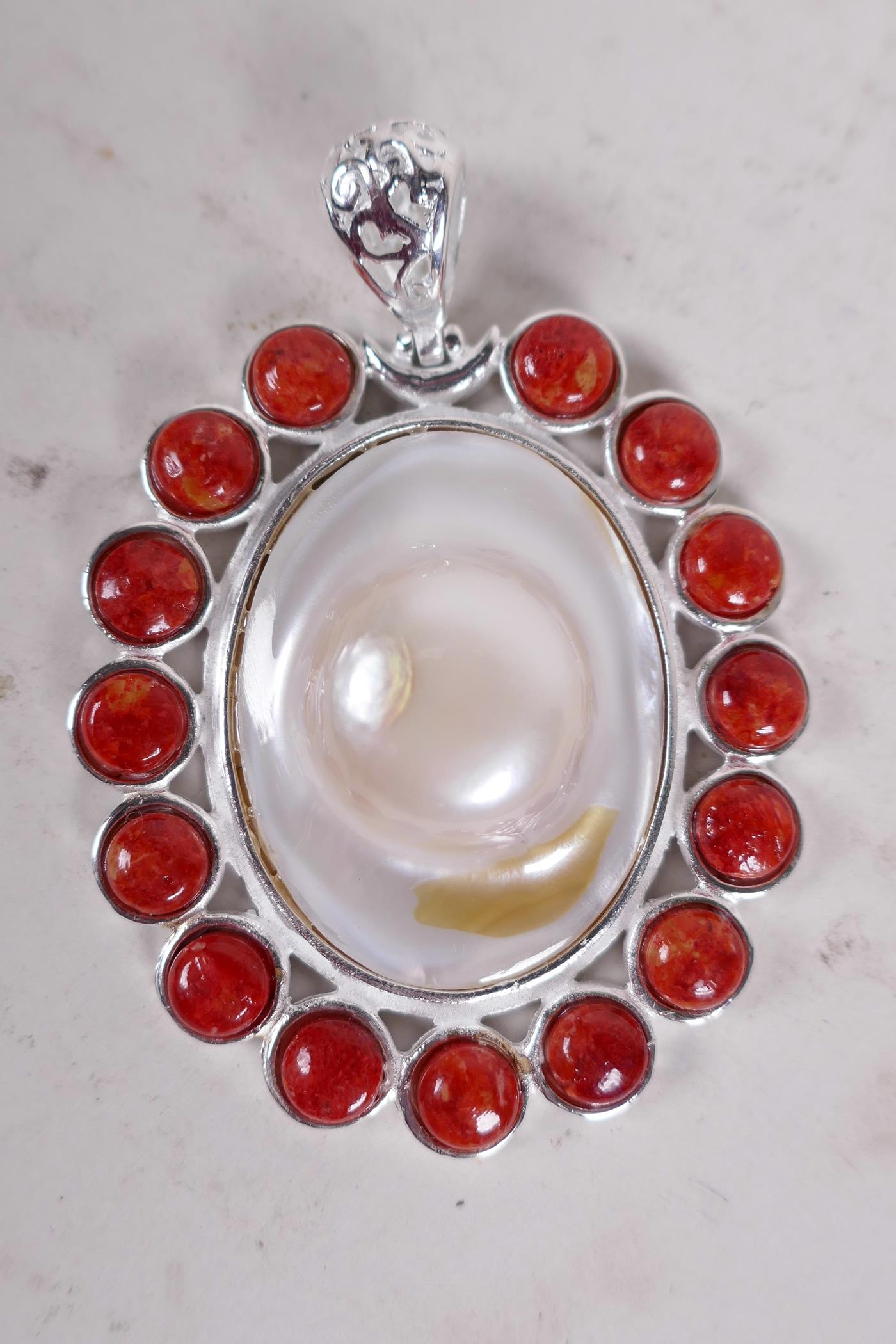 An oval mother of pearl and coral set pendant, 2½" long