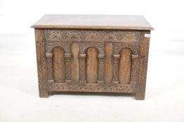 An oak coffer, with carved frieze and three arched panels, raised on stile supports, 36" x 19" x 24"