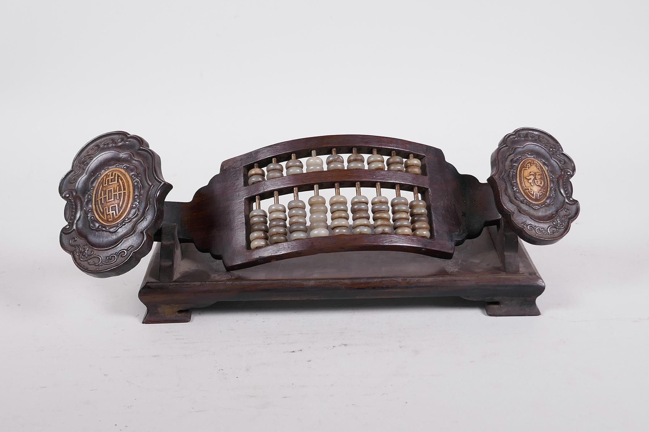 A Chinese carved hardwood abacus and stand in the form of a ruyi, with jade bead counters and