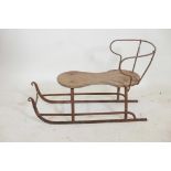 An antique child's sled, wrought iron with a wood seat, 32" x 20"high