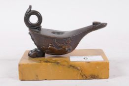 A Grand Tour bronze oil lamp after the antique, with raised satyr decoration, mounted on a marble