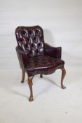 A Georgian style armchair with buttoned leather upholstery and scroll arms, raised on cabriole