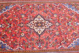 A red ground full pile Persian Sarouk carpet with multicoloured floral design, 82" x 120"