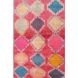 An Iranian washed red ground wool village rug with a multicolour geometric design, 55" x 85"