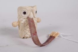 A bone tape measure carved in the form of an owl, 2½"