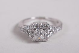 An 18ct white gold Art Deco style dress ring set with a princess cut diamond within a ring of