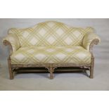 A camel back settee with scroll arms and carved and pierced frame, raised on square supports with