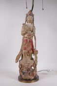 An antique carved and polychrome decorated figure of Quan Yin, mounted on a brass stand table