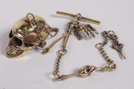 A brass Albert style watch chain with skull and bone decoration, 12½" long