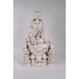 A Chinese blanc de chine porcelain Quan Yin seated on a lotus throne with two child attendants,