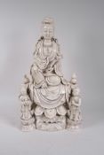 A Chinese blanc de chine porcelain Quan Yin seated on a lotus throne with two child attendants,