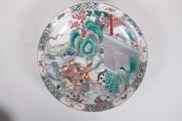 A Chinese famille verte porcelain charger decorated with warriors on horseback, 6 character mark