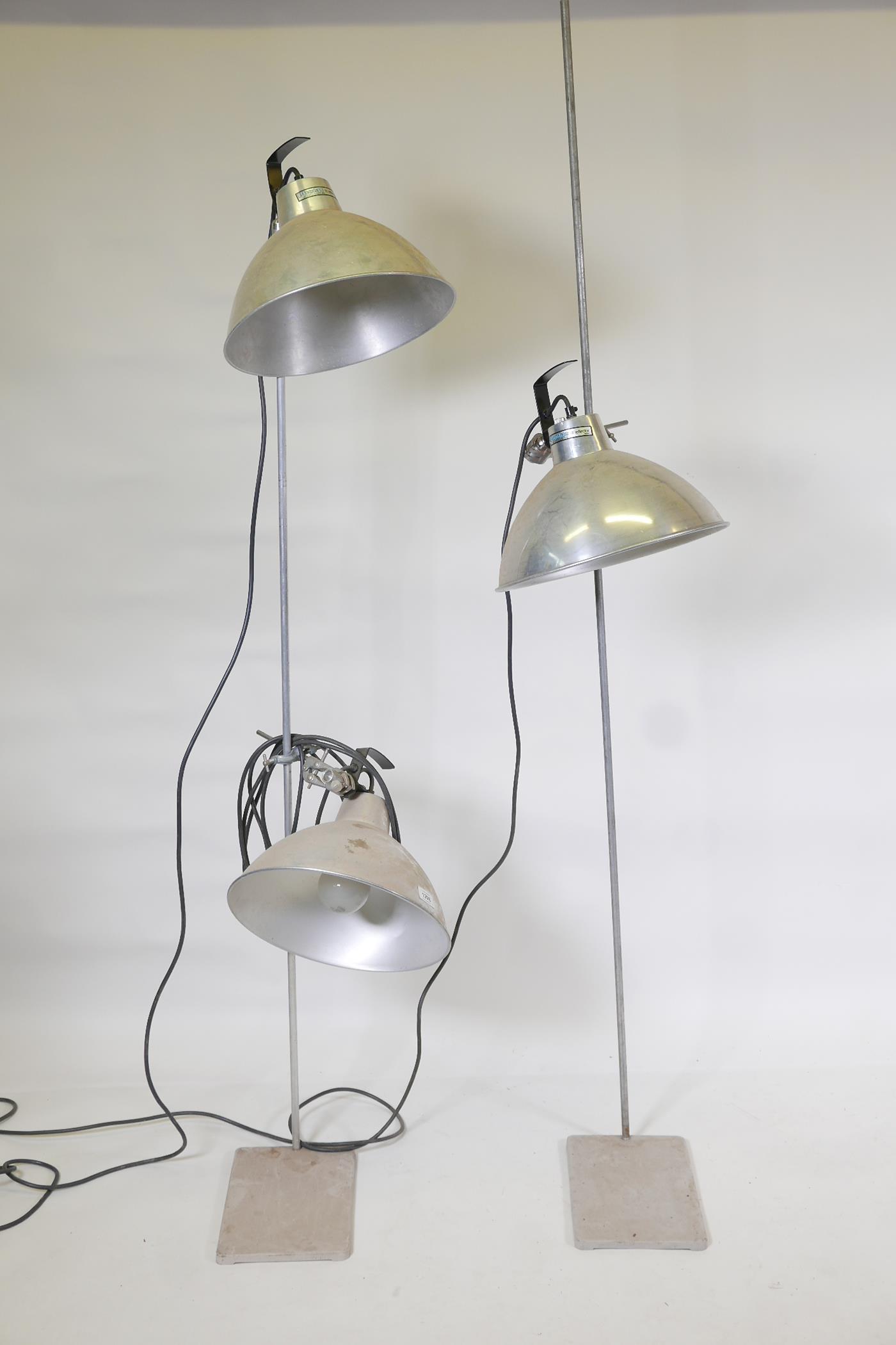 Three aluminium industrial lamps, 13" diameter, and two stands