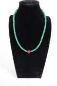 A 130cts emerald gemstone necklace finished with a central natural ruby bead and a silver clasp,