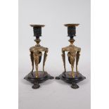 A pair of Regency bronze and ormolu candlesticks with palmette decoration and suspended acorn