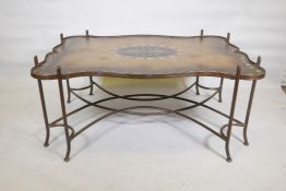 A painted metal framed low table, with hand painted shaped top, raised on sabre supports with