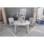 A teak extending garden table and four folding chairs, 71" x 47", 29½" high extended