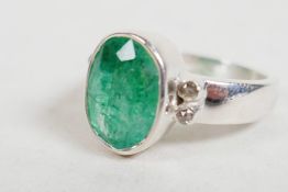 An emerald ring set in sterling silver, stamped 925, oval rose cut with diamond accents on shoulders