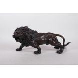 A hollow cast patinated brass figure of a lion, 12" long