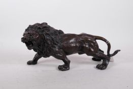A hollow cast patinated brass figure of a lion, 12" long