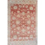 A Pakistani washed red ground wool rug with a floral design and cream borders, 61" x 80"
