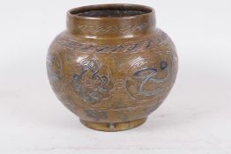 An antique Islamic brass pot decorated with inlaid copper and wire on an engraved background with