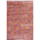 An Afghan rust coloured wool carpet with a repeating blue and rust coloured medallion design, 97"