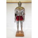A suit of armour with engraved and etched decoration, mounted on a stand with oak base