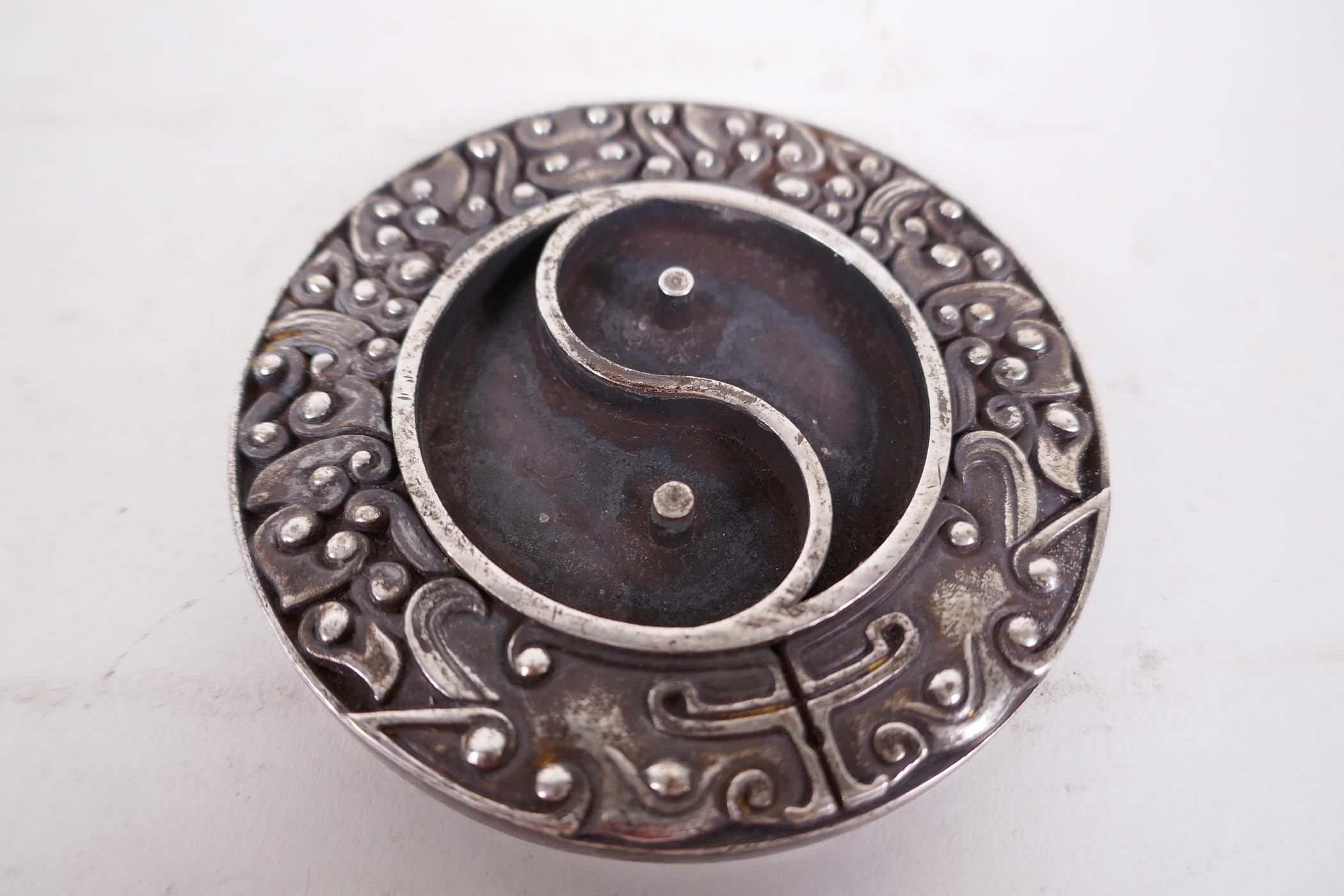 A Chinese white metal ink stone formed as the Yin Yang symbol, 3¼" diameter